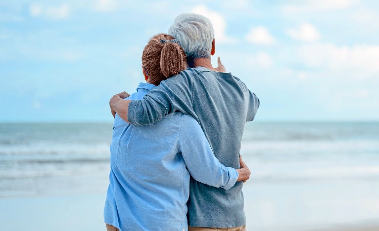 Older couple hugging while looking out onto the ocean